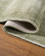 Sage green textured velvet rug with subtle worn vintage distressing throughout
