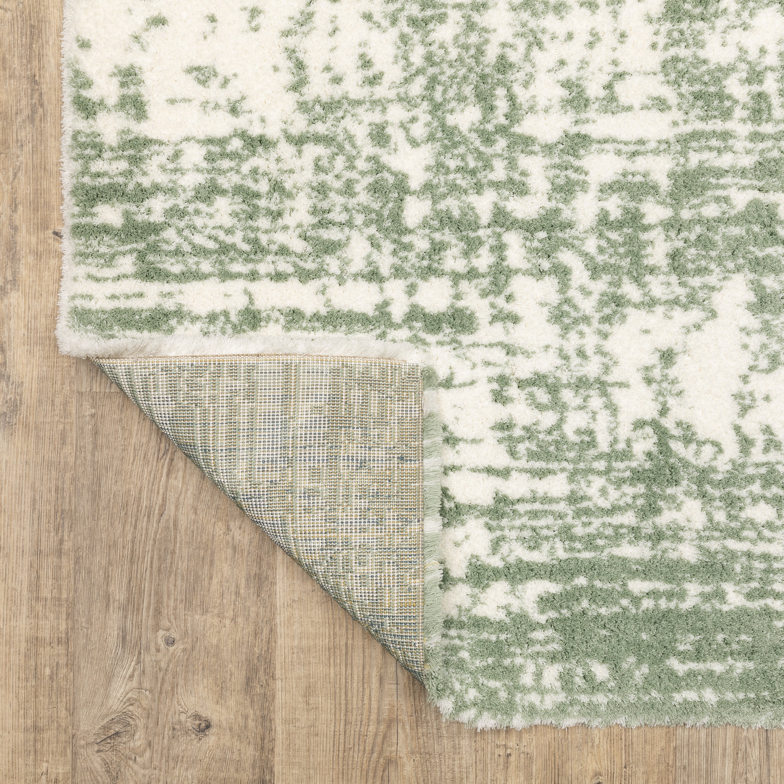 Green and white distressed textured area rug with abstract marbled pattern