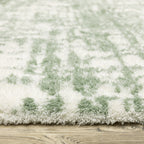 Green and white distressed textured area rug with abstract marbled pattern
