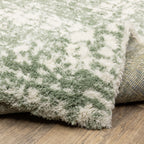Green and white distressed textured area rug with abstract marbled pattern