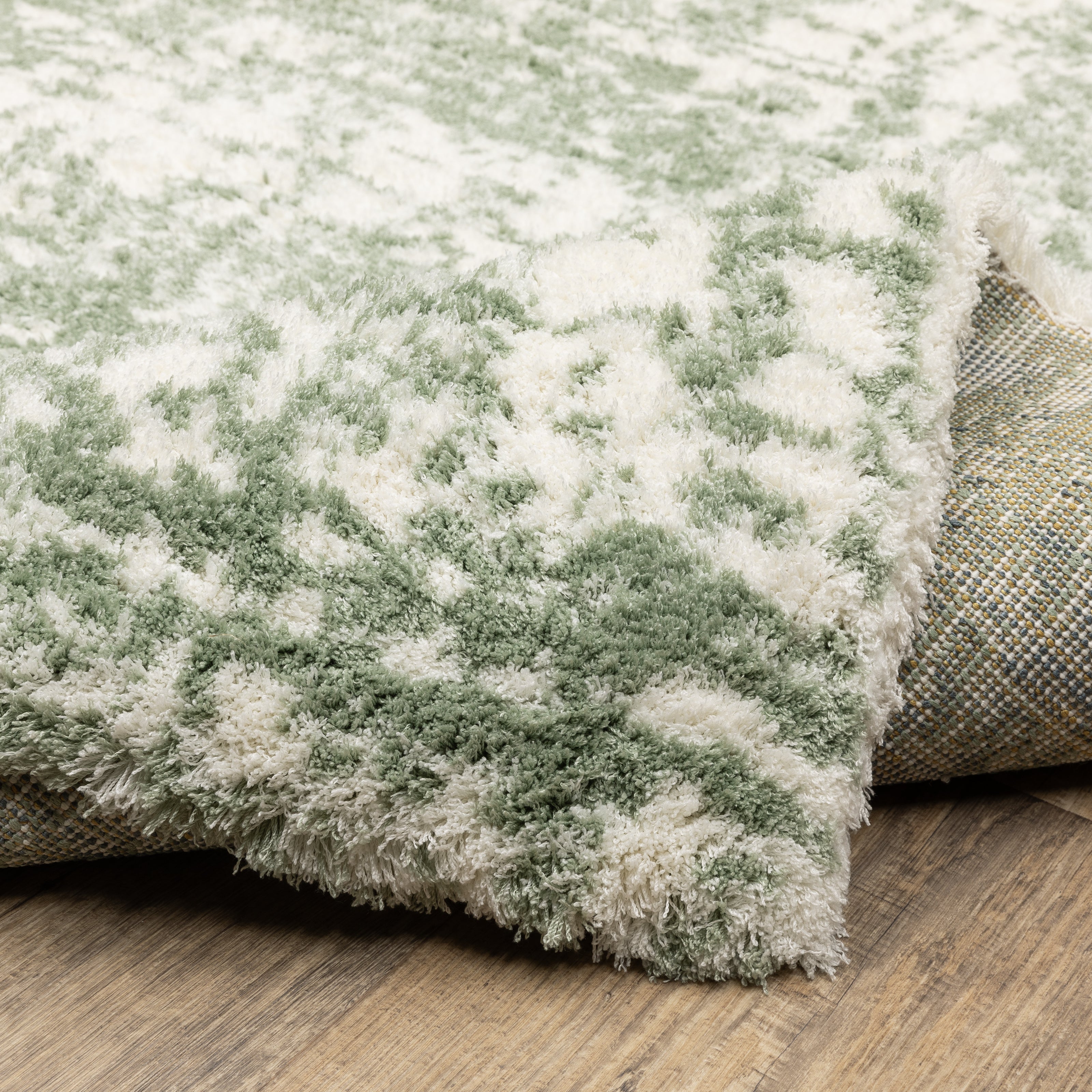 Green and white distressed textured area rug with abstract marbled pattern