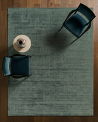 Sage green distressed rug with textured, mottled surface and worn vintage appearance