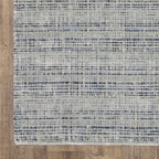 Grey woven rug with dense textured pattern and neutral tones throughout