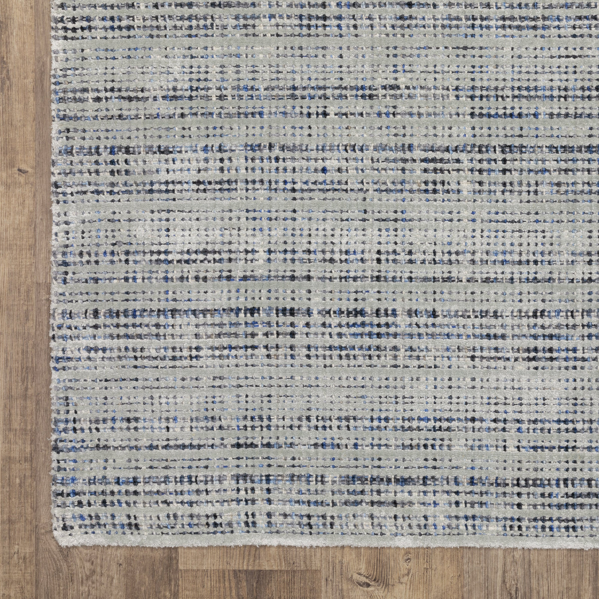 Grey woven rug with dense textured pattern and neutral tones throughout