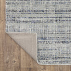 Grey woven rug with dense textured pattern and neutral tones throughout