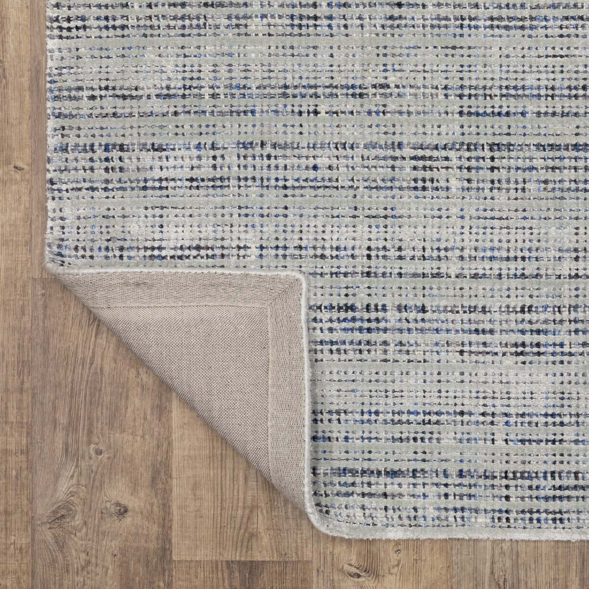 Grey woven rug with dense textured pattern and neutral tones throughout