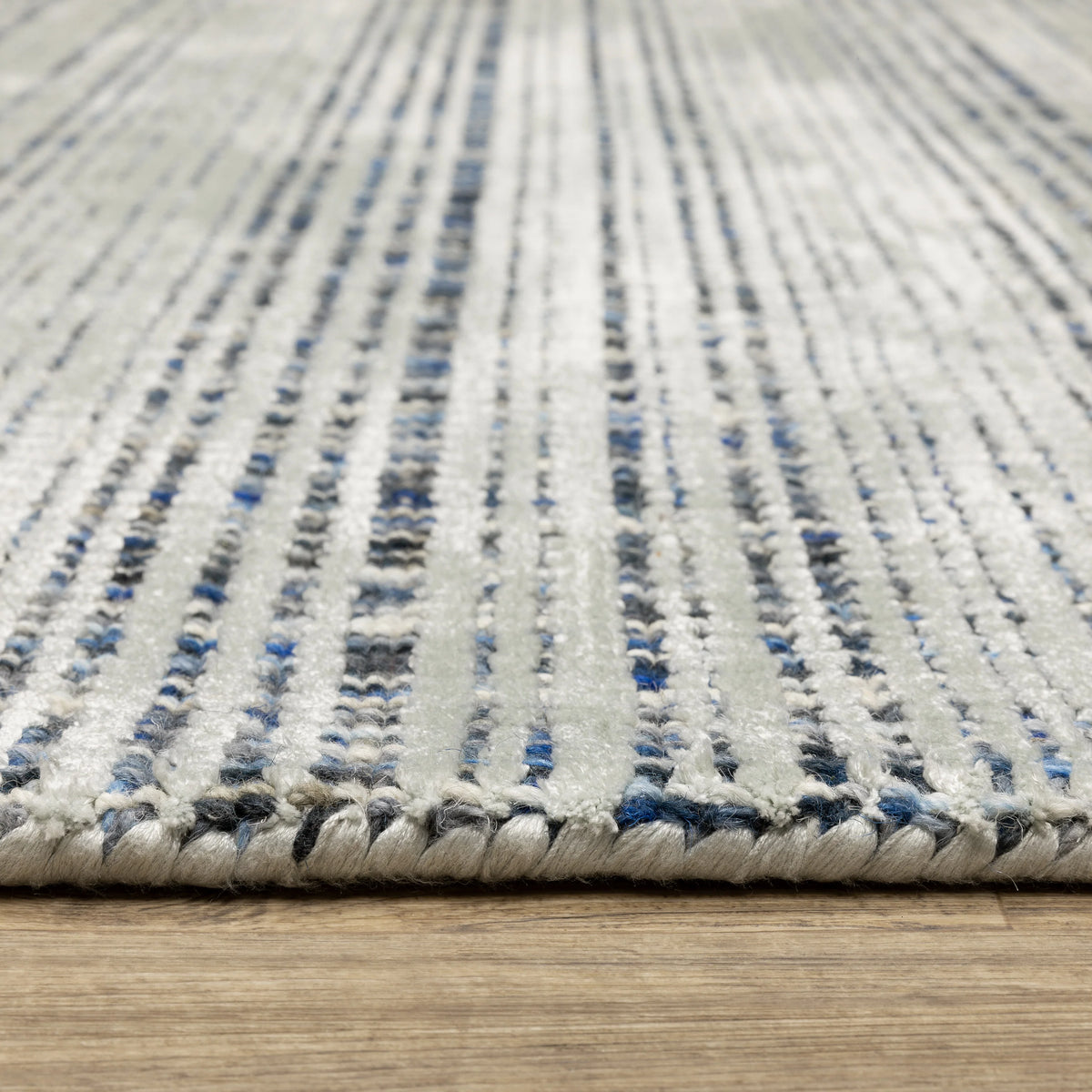 Grey woven rug with dense textured pattern and neutral tones throughout