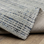 Grey woven rug with dense textured pattern and neutral tones throughout