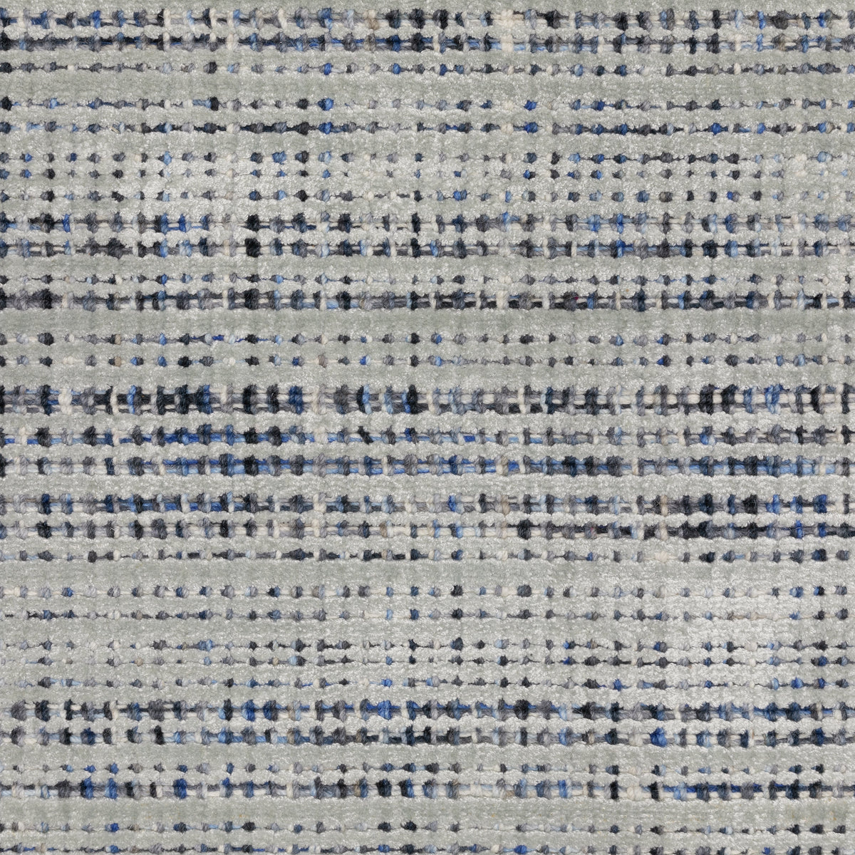 Grey woven rug with dense textured pattern and neutral tones throughout
