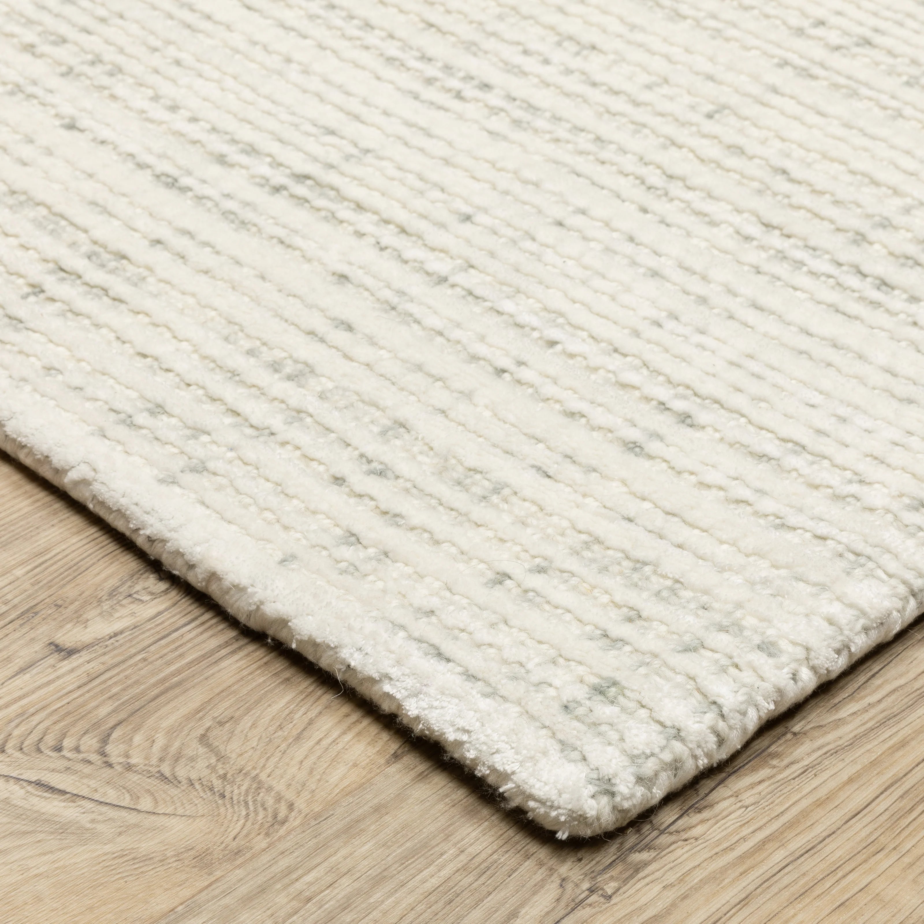 Cream textured wool rug on light wood flooring with visible weave pattern