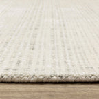 Cream textured wool rug on light wood flooring with visible weave pattern