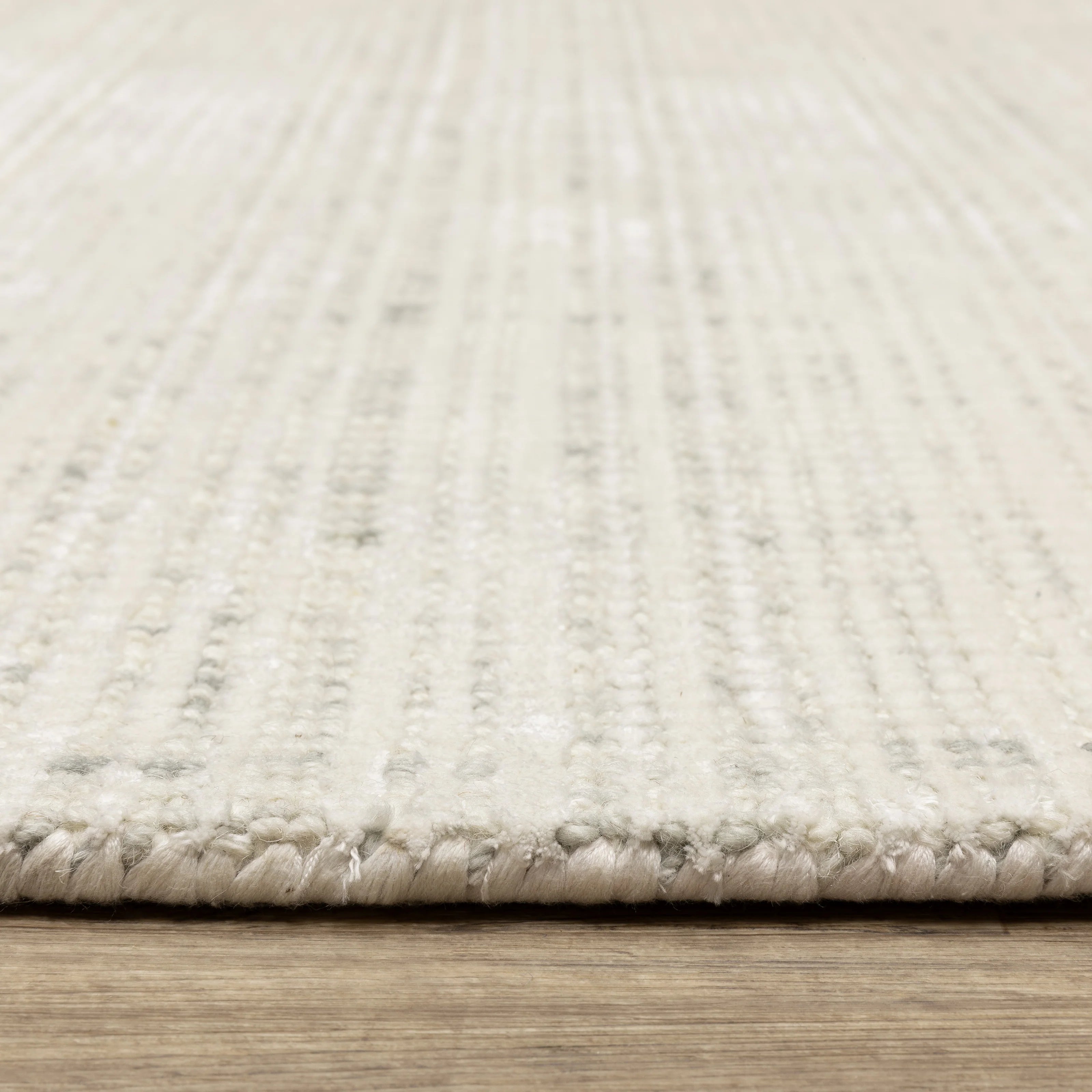 Cream textured wool rug on light wood flooring with visible weave pattern