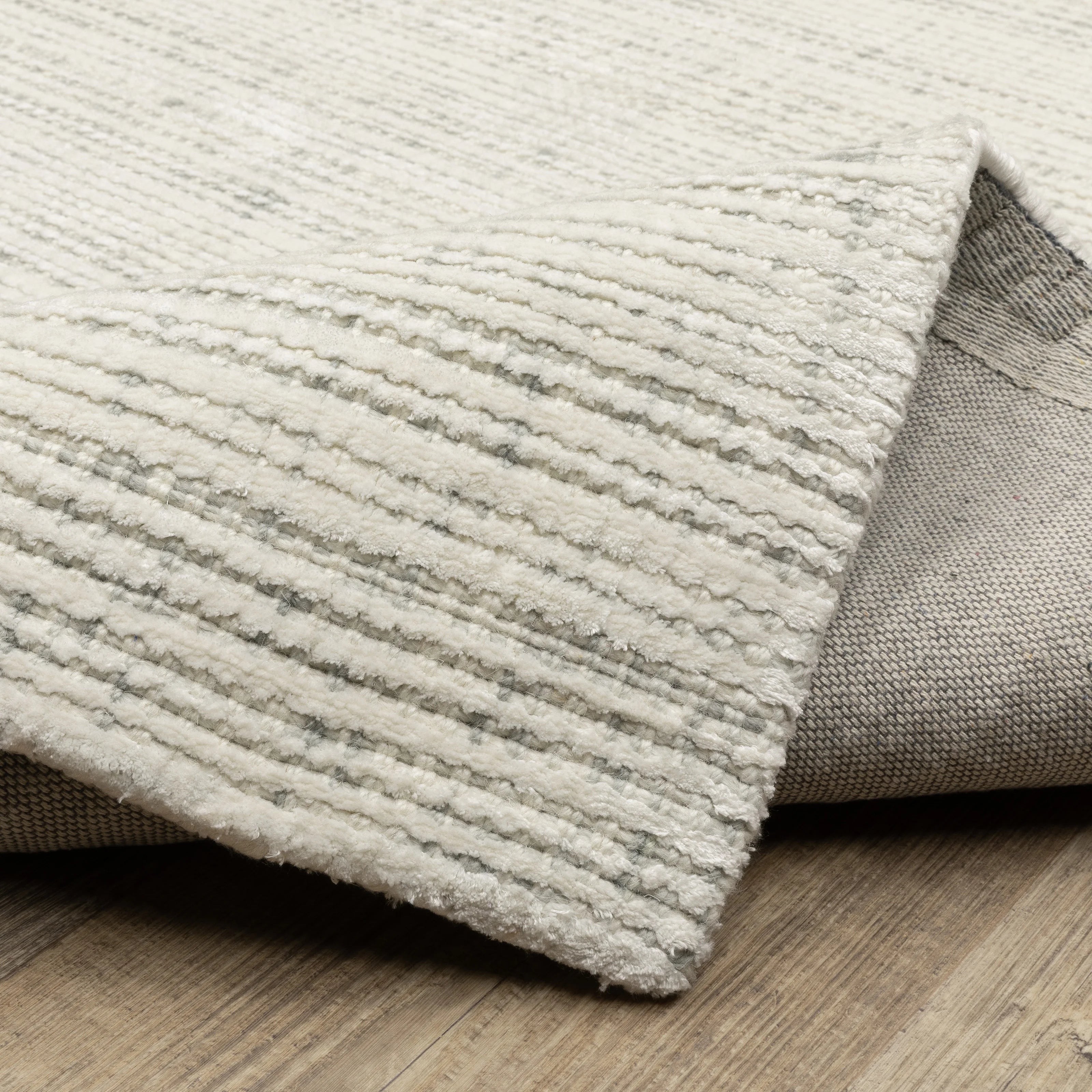 Cream textured wool rug on light wood flooring with visible weave pattern