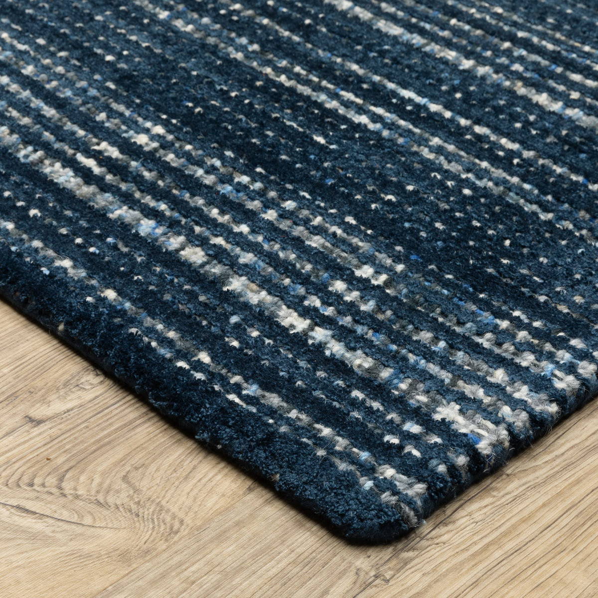 Dark blue textured woven rug with horizontal stripe pattern and neutral accents