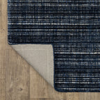 Dark blue textured woven rug with horizontal stripe pattern and neutral accents