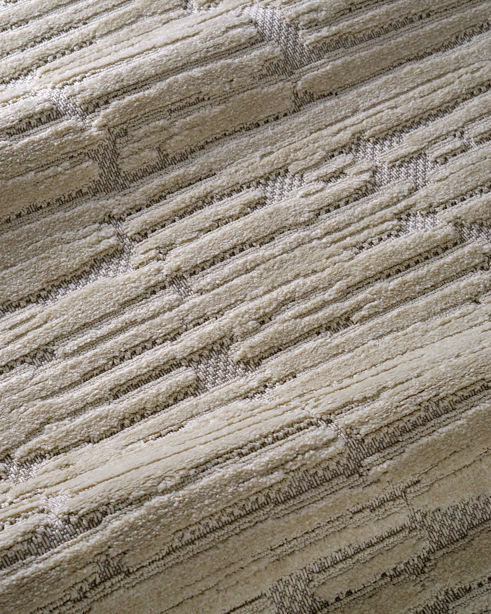 Cream textured rug with geometric brick pattern and subtle tonal details