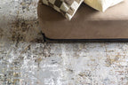 Abstract distressed rug with gold, grey, and cream weathered texture pattern