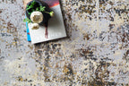 Abstract distressed rug with gold, grey, and cream weathered texture pattern