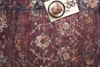 Burgundy distressed rug with ornate floral patterns in cream and rust tones