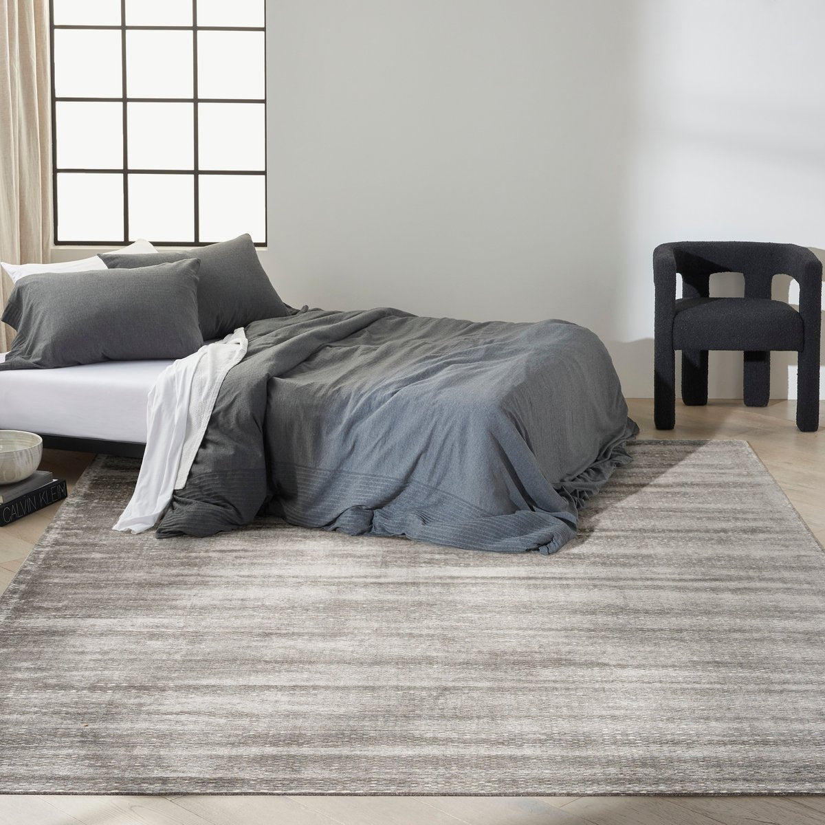 Grey textured rug with subtle horizontal striations and mottled appearance throughout