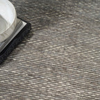 Grey textured rug with subtle horizontal striations and mottled appearance throughout