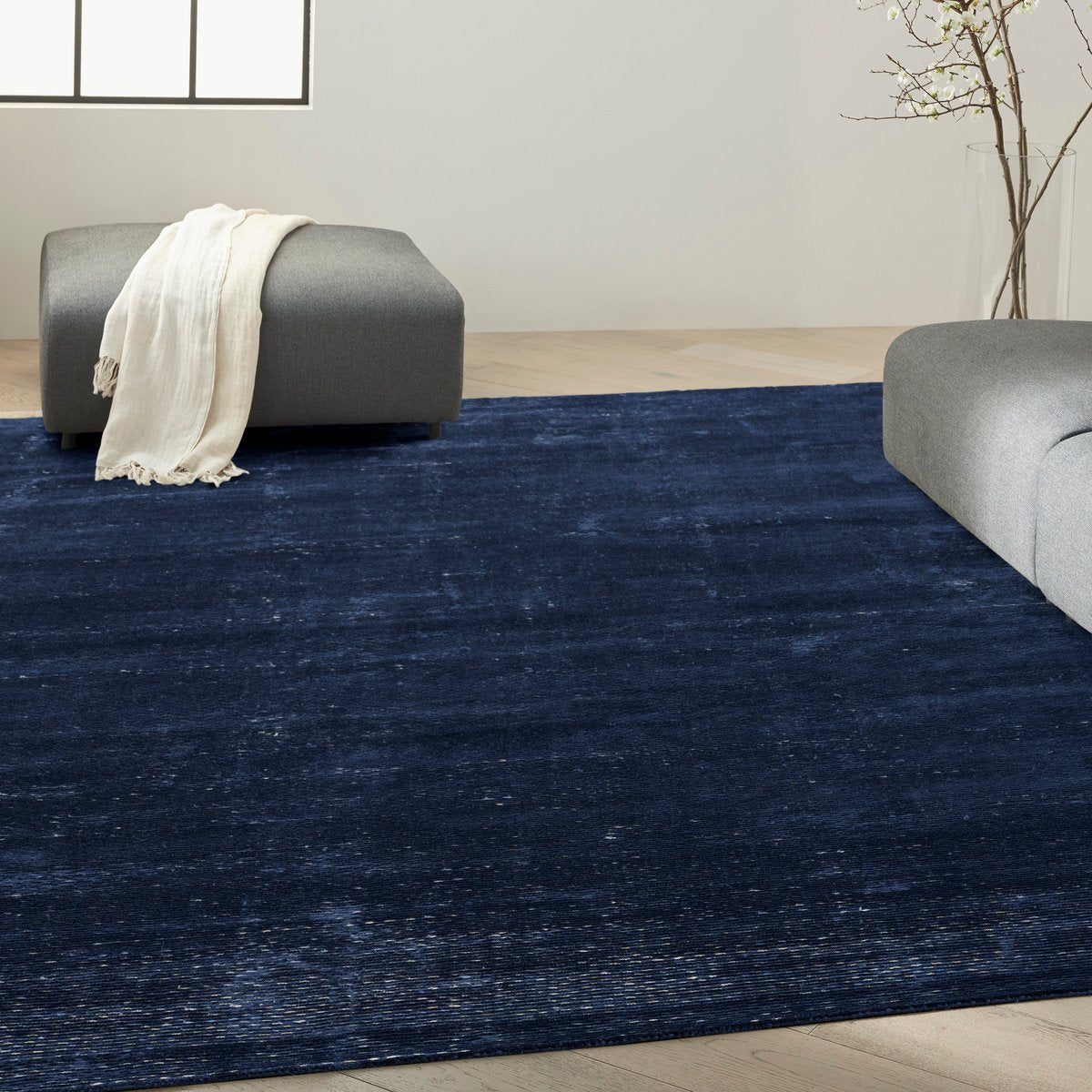 Dark blue textured area rug with subtle horizontal striations and woven pattern