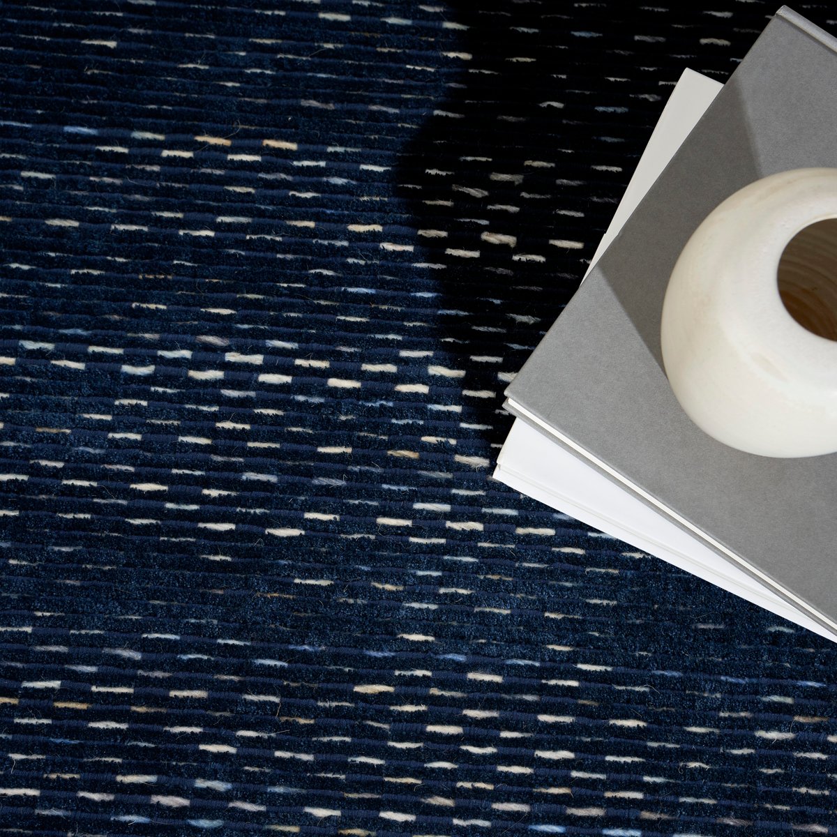 Dark blue textured area rug with subtle horizontal striations and woven pattern
