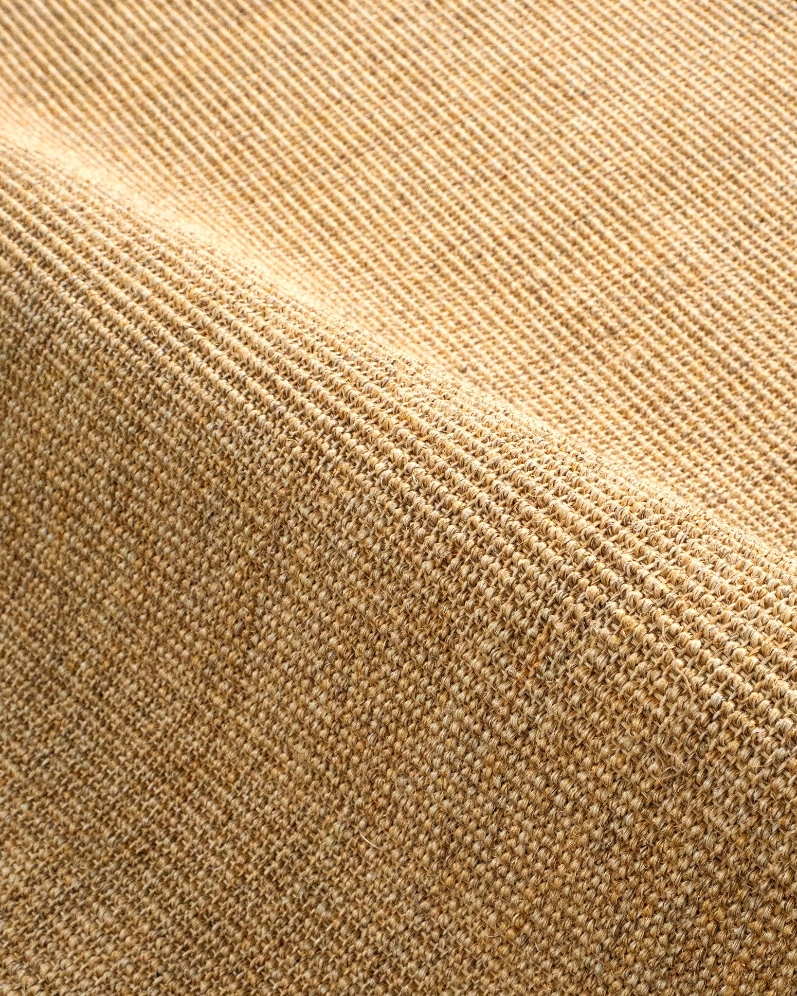 Natural woven jute rug with tight ribbed texture in golden tan color