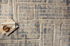Beige and blue abstract geometric patterned rug with textured wool surface