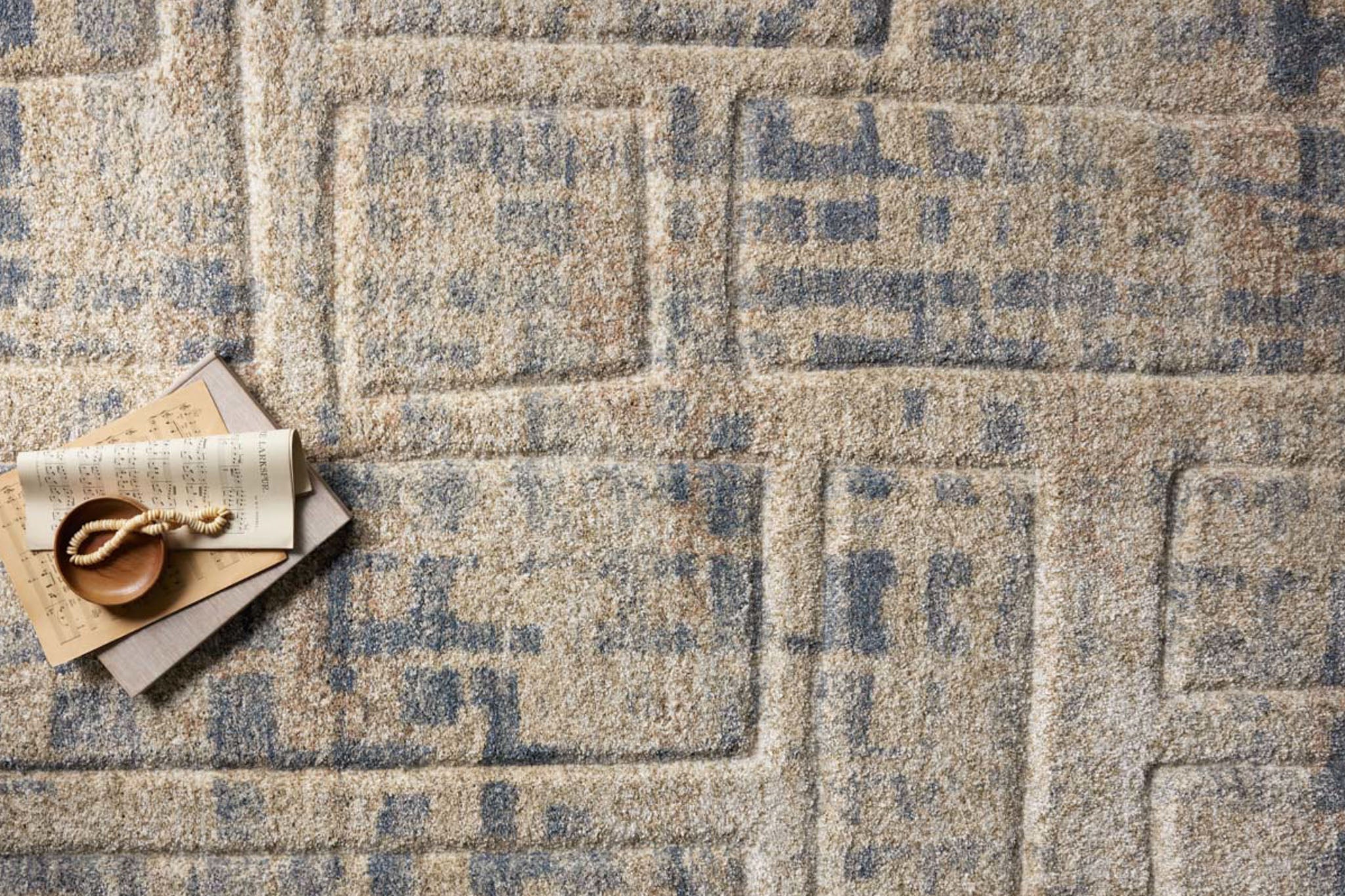 Beige and blue abstract geometric patterned rug with textured wool surface