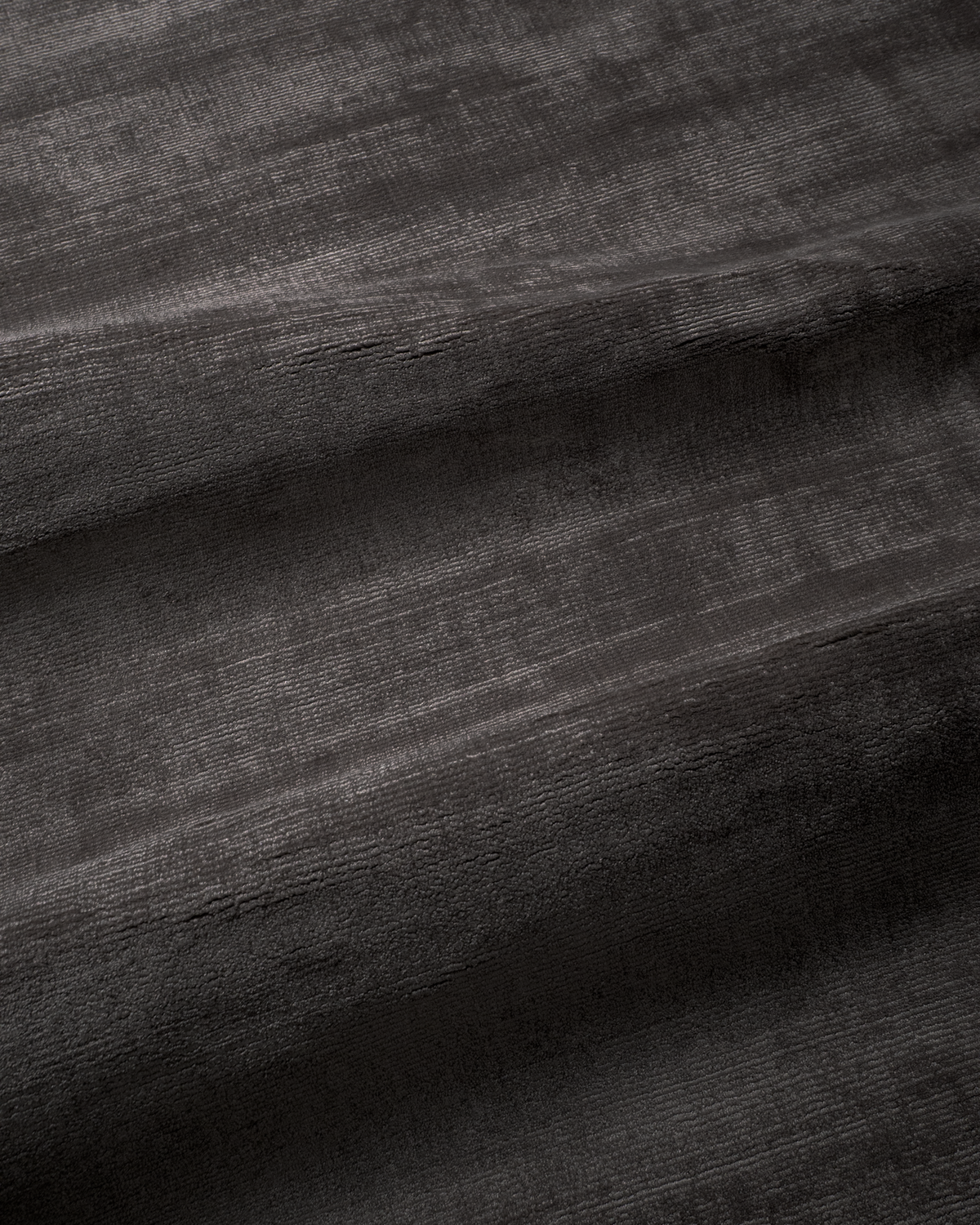 Amara viscose hand-loomed area rug in Black, draped to show the sheen