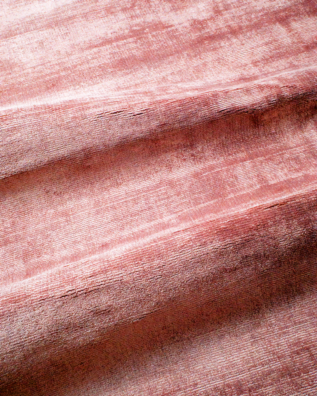 Amara viscose hand-loomed area rug in Coral Pink, draped to show the sheen