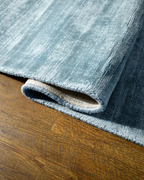 Amara viscose hand-loomed area rug in Dark Cyan, curled edge detail