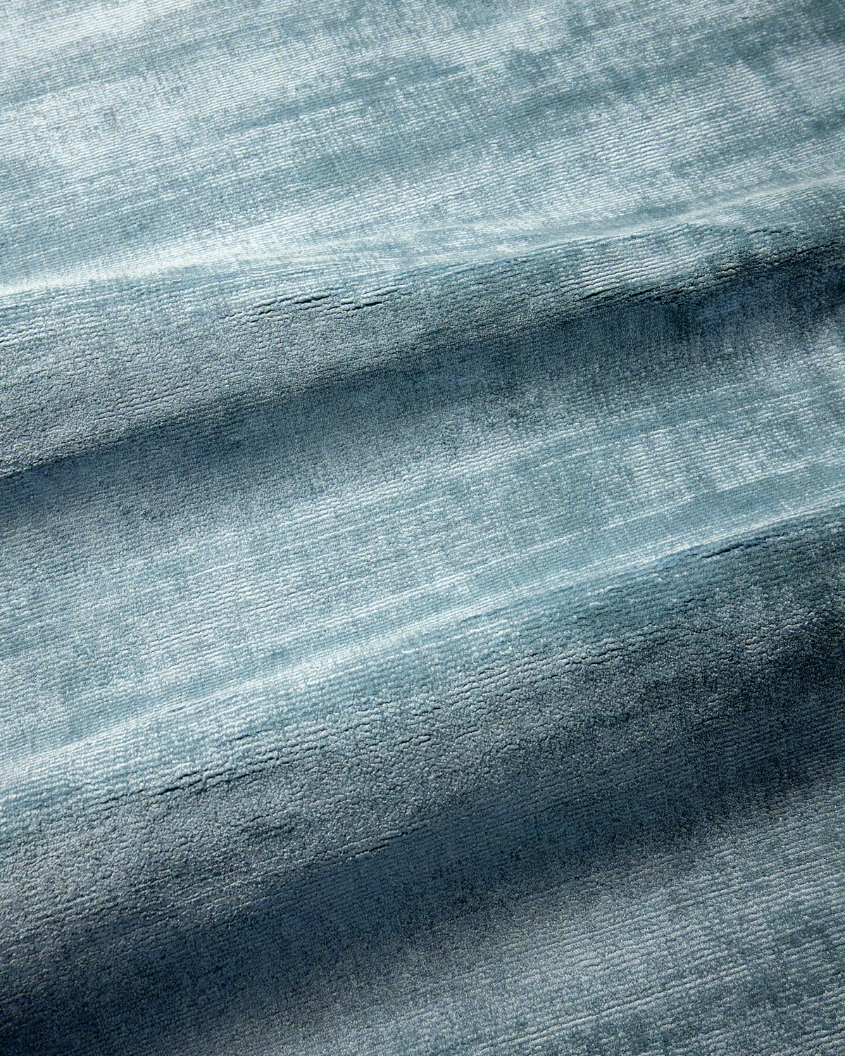 Amara viscose hand-loomed area rug in Dark Cyan, draped to show the sheen