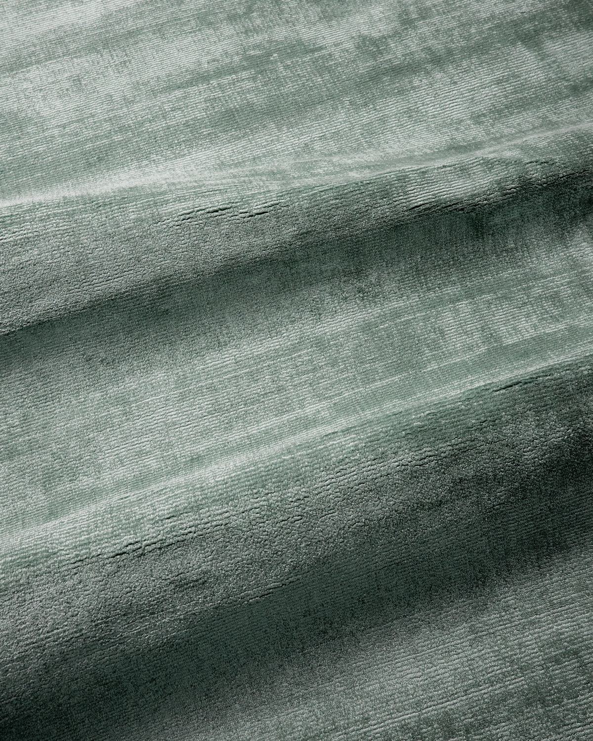 Amara viscose hand-loomed area rug in Evergreen, draped to show the sheen