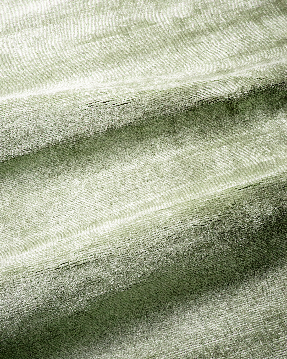 Amara viscose hand-loomed area rug in Sage, draped to show the sheen