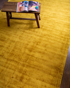 Amara viscose hand-loomed area rug in Yellow, styled in a living room