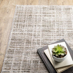 Beige textured area rug with abstract grid pattern on light wood flooring