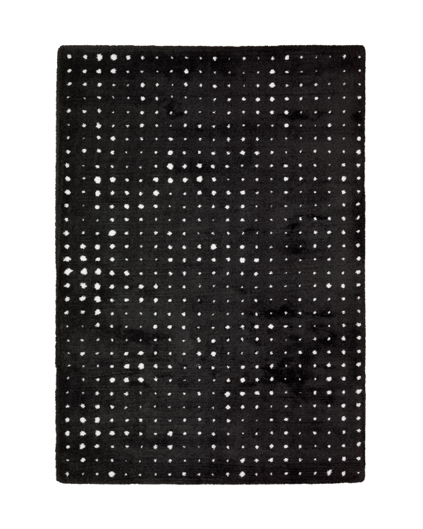 Black wool rug with white polka dot pattern and textured pile surface