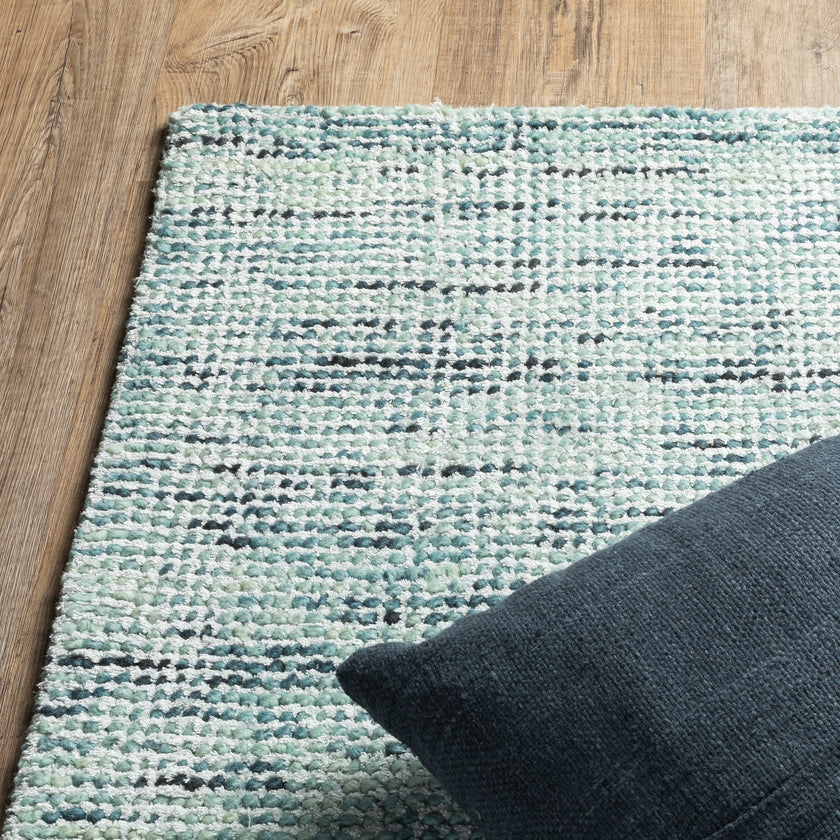 Light blue textured area rug in modern bedroom with wooden furniture