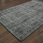 Modern gray textured rug with woven pattern on dark wood flooring
