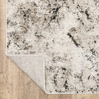 Modern distressed rug with black speckled pattern on cream background texture