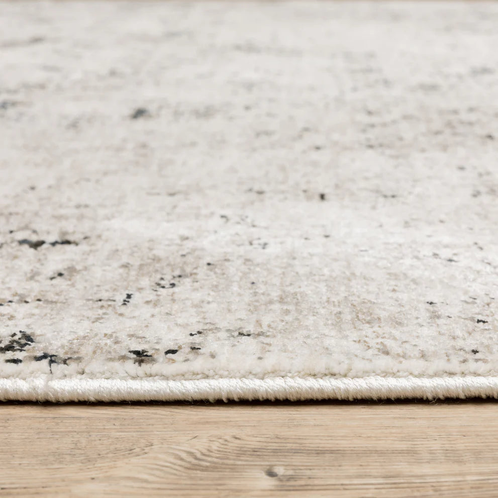 Modern distressed rug with black speckled pattern on cream background texture