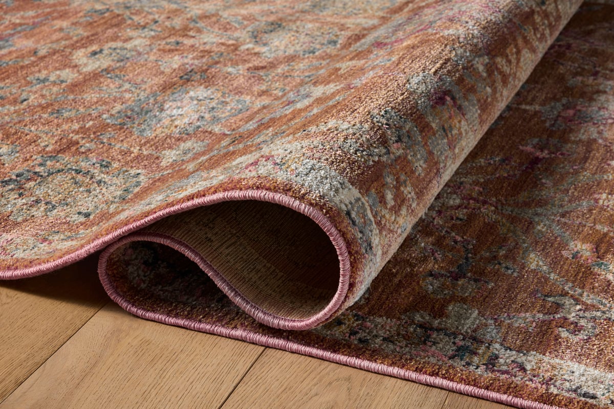 Vintage-style area rug with rust red background and ornate floral damask pattern in cream and blue tones